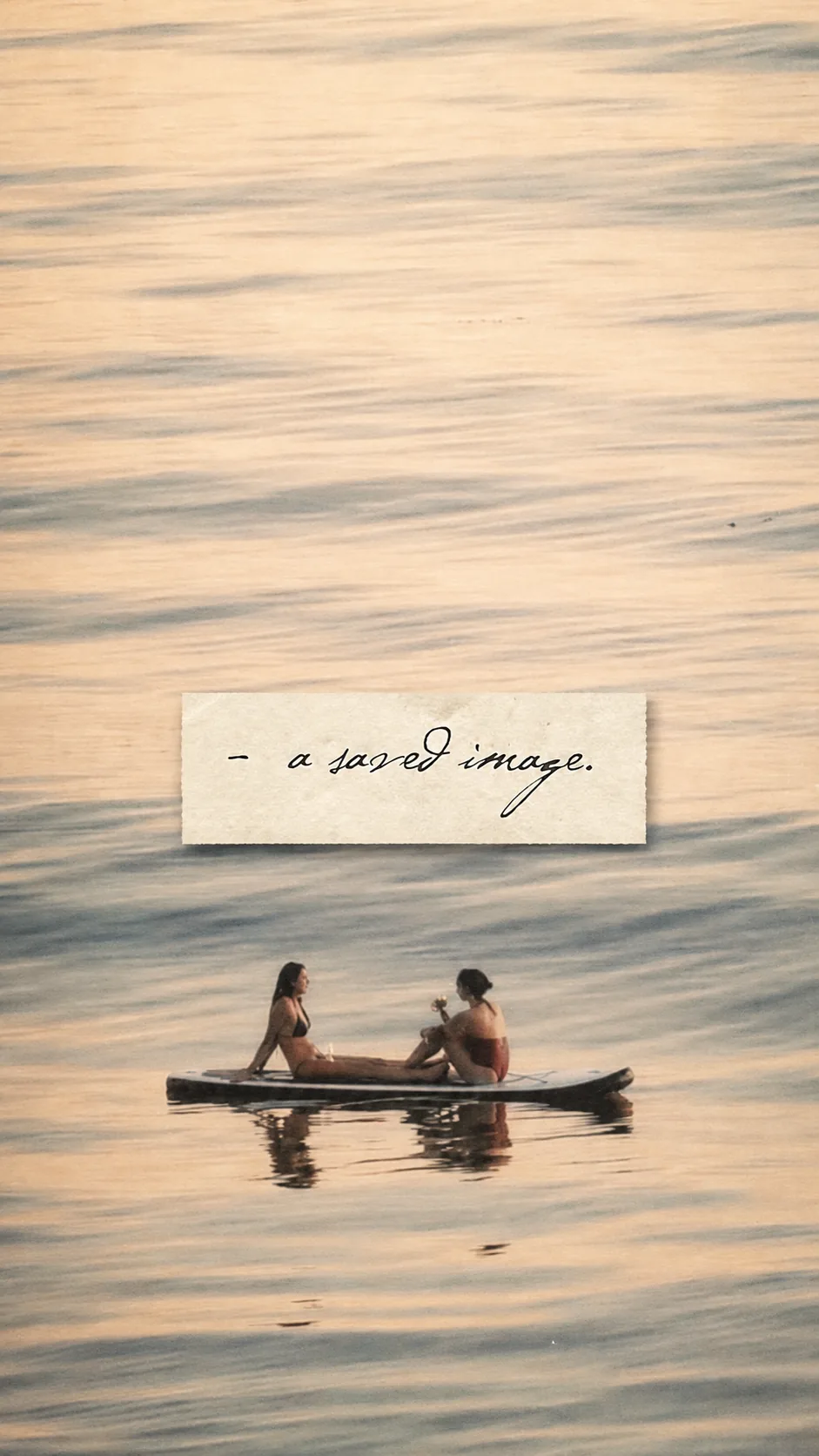 Two people sit on a paddleboard at sunset